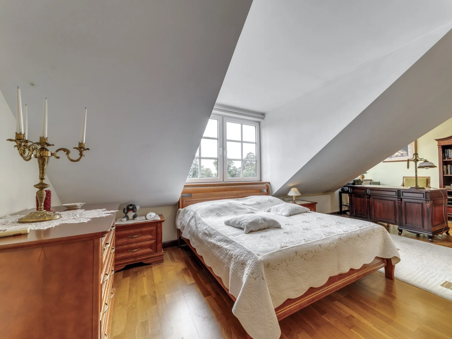 Przytulna sypialnia na antresoli z drewnianymi meblami i dużym łóżkiem